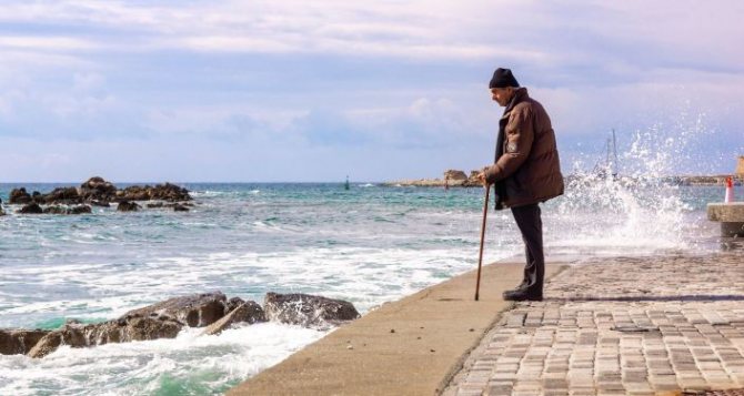 An elderly man walks by the sea, archival photo