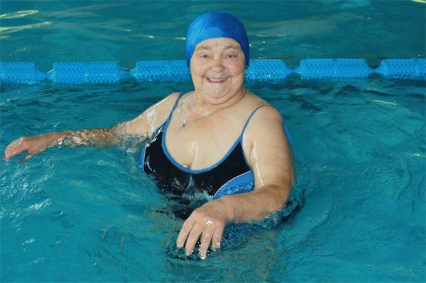 Счастливая пожилая женщина плавает в бассейне