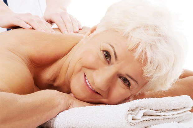 Улыбающейся пожилой женщине делают массаж