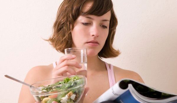 женщина пьет из стакана и ест салат